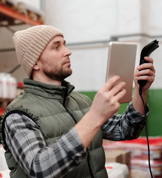 Warehouse coordinator checking palletised stock records on a digital tablet