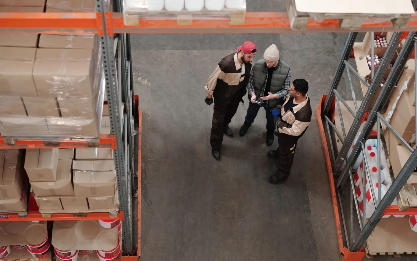 Warehouse staff reviewing delivered palletised cartons against an inspection clipboard