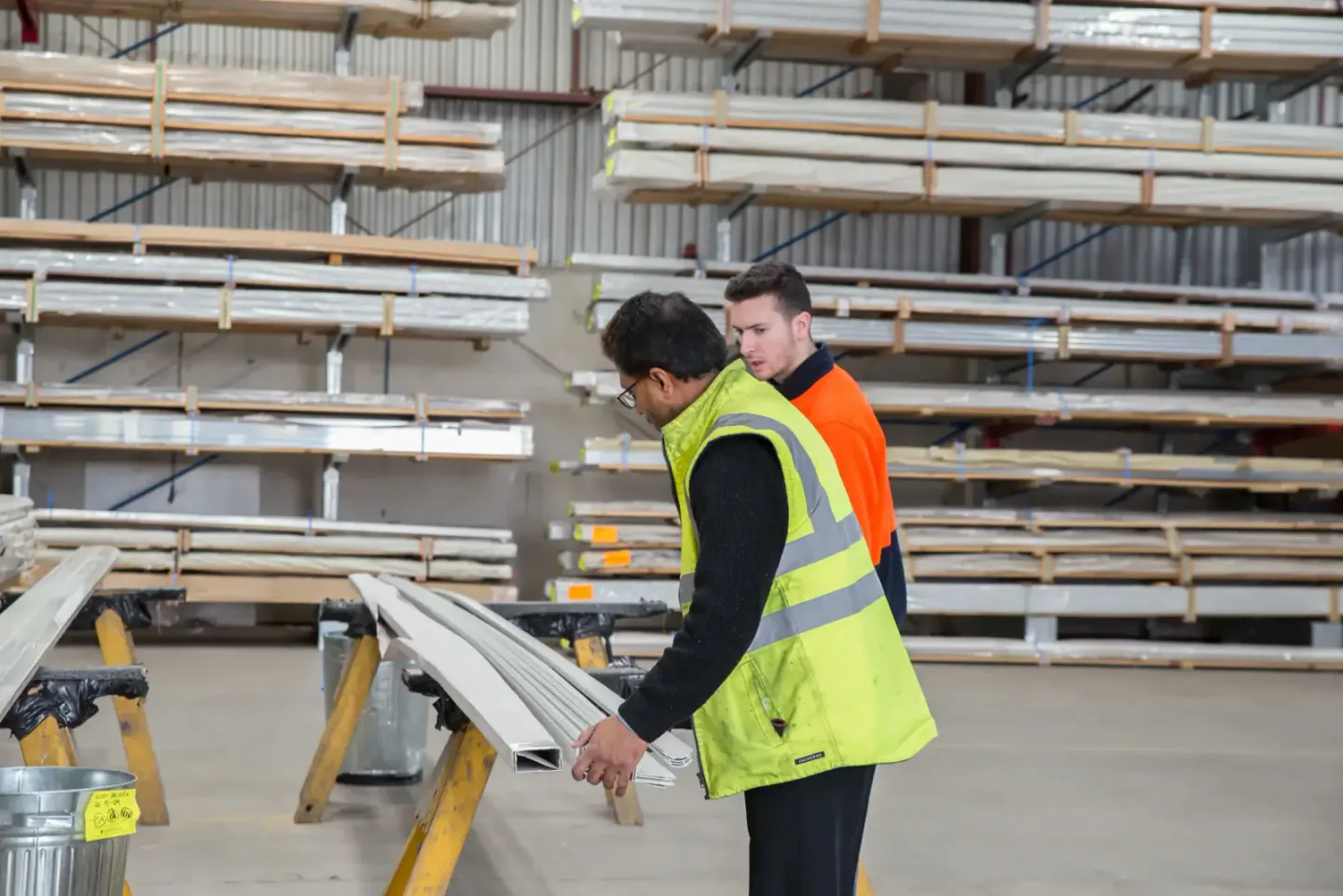 Two inspectors checking metal building profiles and construction materials in a facility