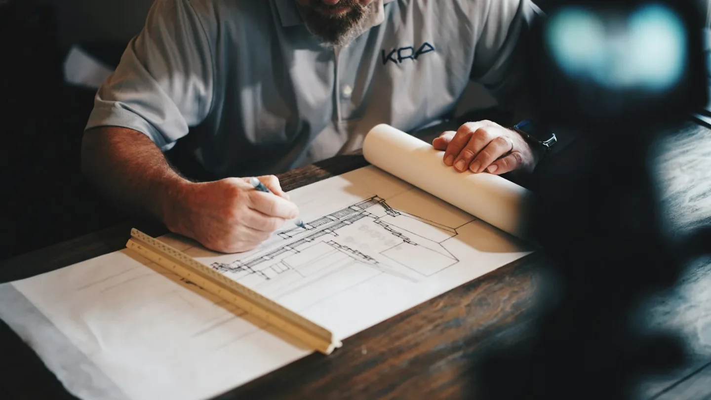 Reviewing technical drawings and documenting product requirements at a desk